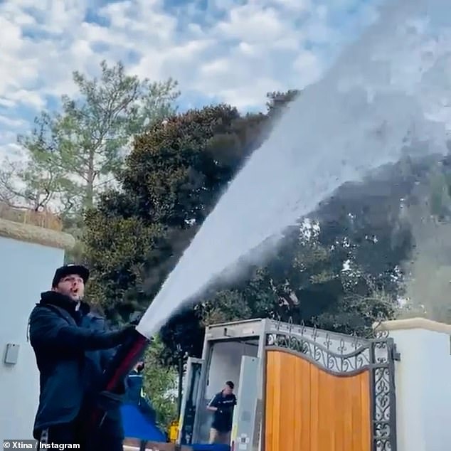 Let it Fall: The comic star posted a video of a man washing his gated yard in snow, on a white Christmas in Beverly Hills, with a bounce house